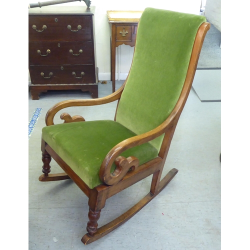 251 - A late Victorian mahogany showwood framed, open arm rocking chair, upholstered in green fabric