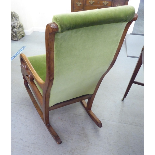 251 - A late Victorian mahogany showwood framed, open arm rocking chair, upholstered in green fabric