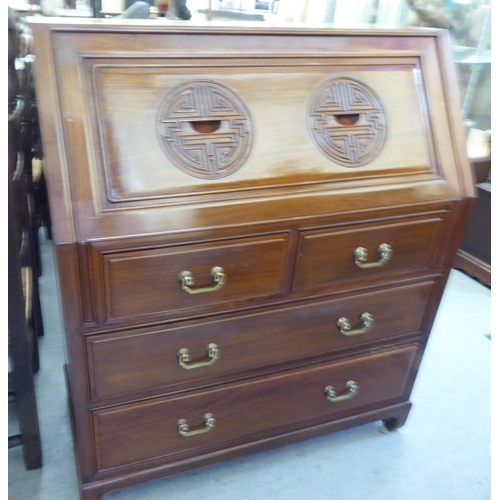 282 - A modern Chinese fruitwood bureau with a fall flap, over two short/two long drawers, raised on block... 