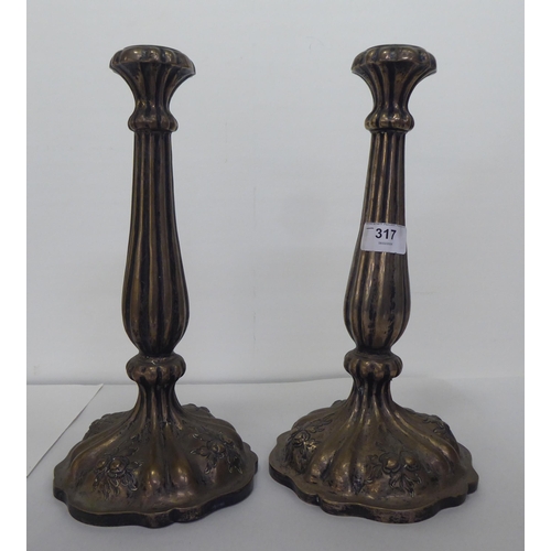 317 - A pair of late 19thC Continental white metal candlesticks, each with a reeded column, on a circular ... 