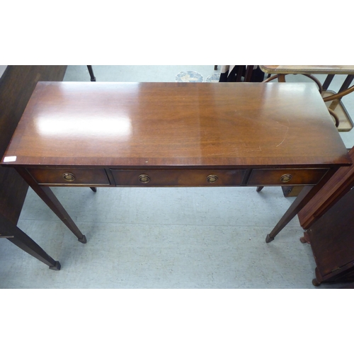 33 - A modern mahogany finished three drawer serving table with cock beading and brass ring handles, rais... 