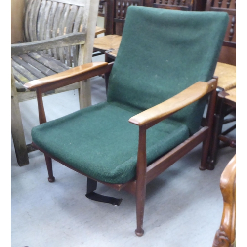 358 - A 1970s teak framed open arm chair with semi-reclining action, raised on turned legs