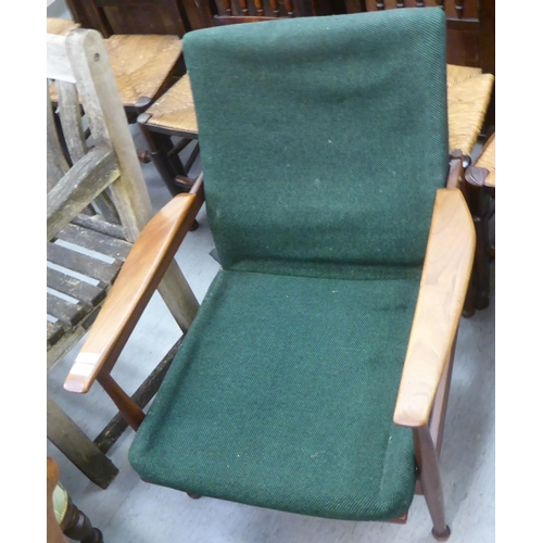 358 - A 1970s teak framed open arm chair with semi-reclining action, raised on turned legs