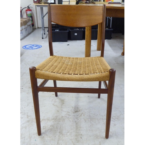 36 - A set of six 1970s teak framed panelled back dining chairs, the woven cane seats raised on turned le... 