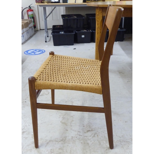 36 - A set of six 1970s teak framed panelled back dining chairs, the woven cane seats raised on turned le... 