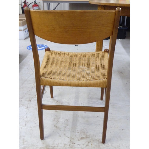 36 - A set of six 1970s teak framed panelled back dining chairs, the woven cane seats raised on turned le... 