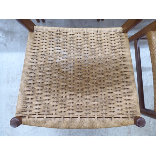 36 - A set of six 1970s teak framed panelled back dining chairs, the woven cane seats raised on turned le... 