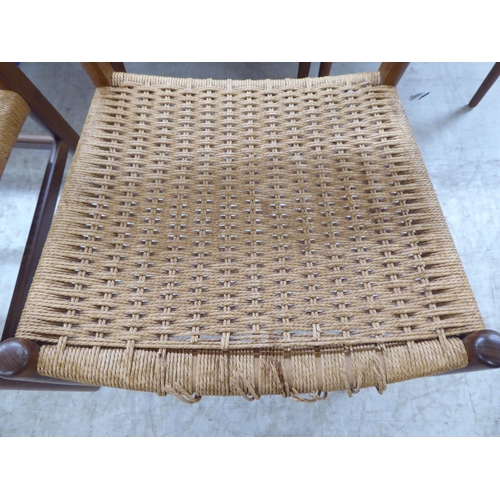 36 - A set of six 1970s teak framed panelled back dining chairs, the woven cane seats raised on turned le... 