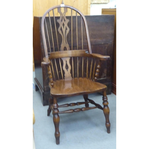 370 - A 20thC stained beech and oak framed high hoop, splat and spindle back Windsor arm chair, the solid ... 