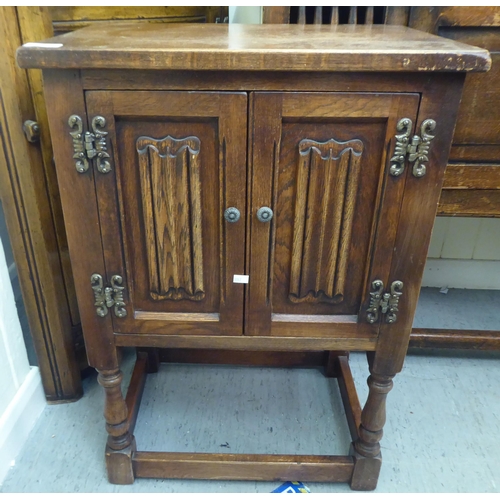 382 - Three items of 20thC Old English style oak furniture: to include a one piece, partially glazed corne... 