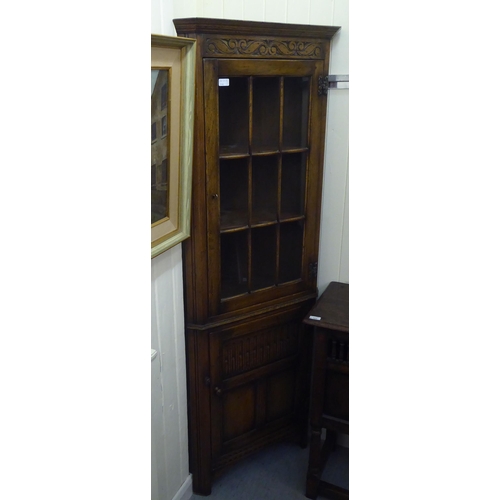 382 - Three items of 20thC Old English style oak furniture: to include a one piece, partially glazed corne... 