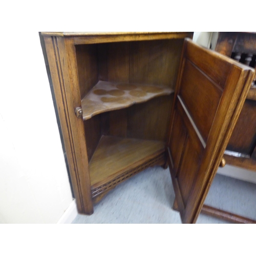 382 - Three items of 20thC Old English style oak furniture: to include a one piece, partially glazed corne... 