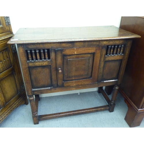 382 - Three items of 20thC Old English style oak furniture: to include a one piece, partially glazed corne... 