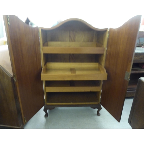 51 - A 1930s walnut finished compactum with an arched top, enclosed by a pair of full height doors, raise... 