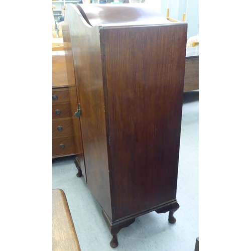 51 - A 1930s walnut finished compactum with an arched top, enclosed by a pair of full height doors, raise... 