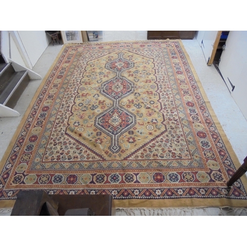 163 - A Tabriz style carpet with three central motifs, bordered by repeating stylised designs, on a beige ... 