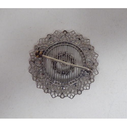 124 - A white metal wire and filigree style diamond set, circular and foliate design brooch