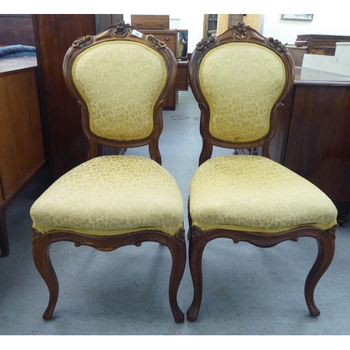 169 - A pair of Edwardian carved hardwood framed salon chairs with shield shape backs and braided old gold... 