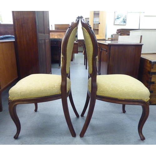 169 - A pair of Edwardian carved hardwood framed salon chairs with shield shape backs and braided old gold... 