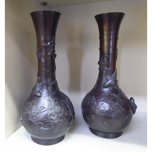 177 - A pair of early 20thC Japanese cast bronze bottle vases with narrow necks and flared rims, decorated... 