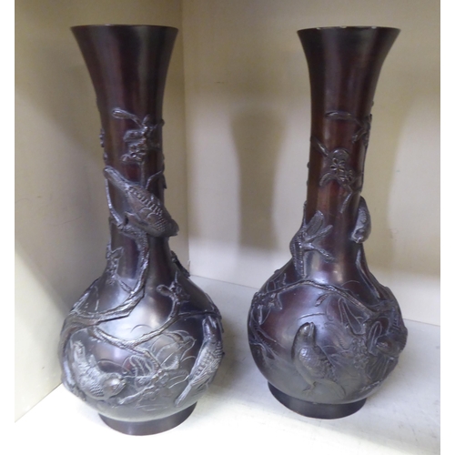 177 - A pair of early 20thC Japanese cast bronze bottle vases with narrow necks and flared rims, decorated... 