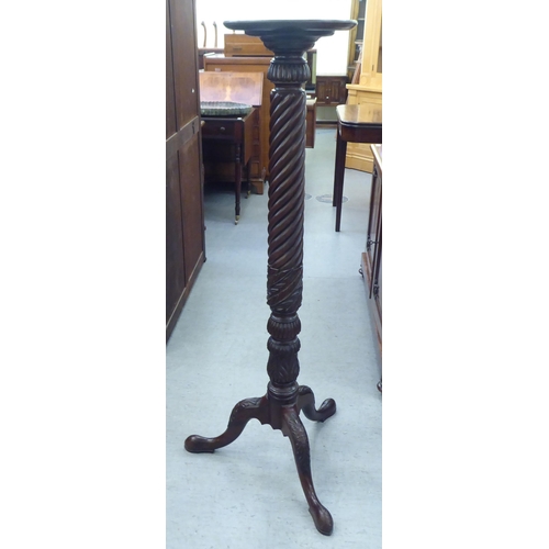 184 - A Victorian style mahogany torchere with a turned plate top, over a wrythen carved column, raised on... 