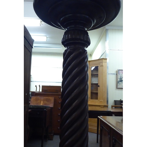 184 - A Victorian style mahogany torchere with a turned plate top, over a wrythen carved column, raised on... 