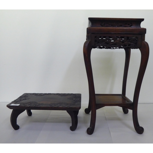 192 - An early 20thC Chinese carved hardwood vase stand with an undershelf, raised on scrolled, cabriole l... 