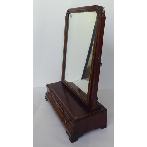 193 - A Georgian carved parcel gilt and mahogany toilet mirror, the plate pivoting on angled horns and a t... 