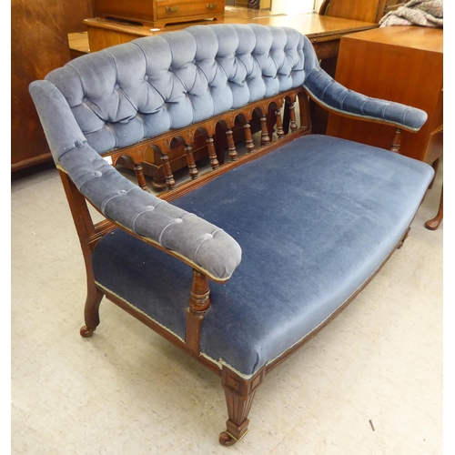 194 - An Edwardian mahogany showwood framed salon settee with a curved back and open arms, part button uph... 