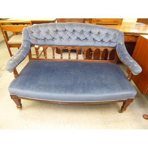 194 - An Edwardian mahogany showwood framed salon settee with a curved back and open arms, part button uph... 