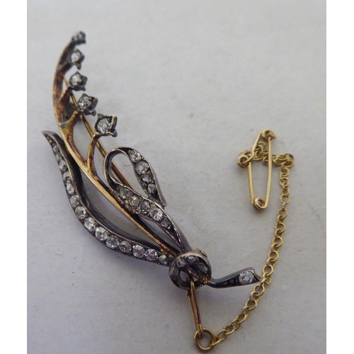 201 - A bi-coloured metal free-flowing foliate design and diamond set brooch 