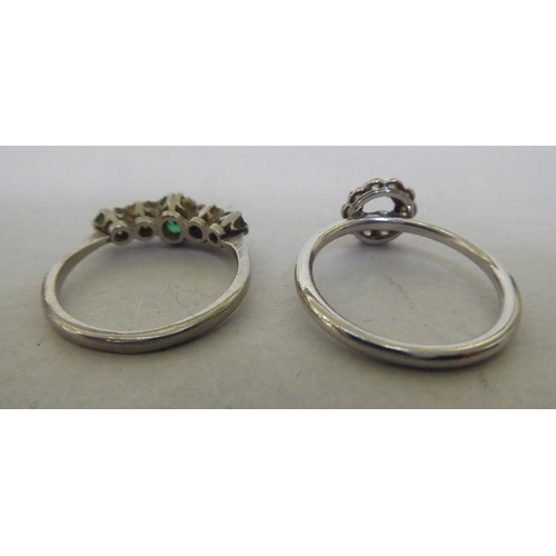 204 - A platinum ring, set with alternating diamonds and emeralds; and another white metal floral design d... 