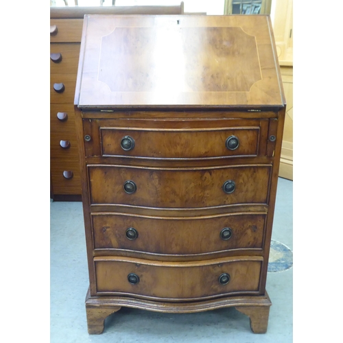 222 - A lady's modern yewwood finished and string inlaid bow front desk, the fall flap with a scriber and ... 