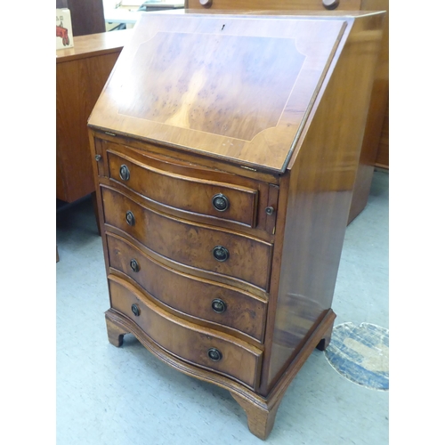 222 - A lady's modern yewwood finished and string inlaid bow front desk, the fall flap with a scriber and ... 