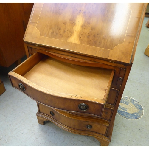 222 - A lady's modern yewwood finished and string inlaid bow front desk, the fall flap with a scriber and ... 