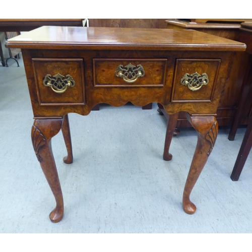 231 - A Georgian style walnut veneered lowboy with a burr veneered and string inlaid top, over three drawe... 