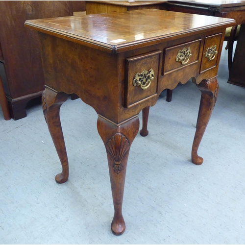 231 - A Georgian style walnut veneered lowboy with a burr veneered and string inlaid top, over three drawe... 