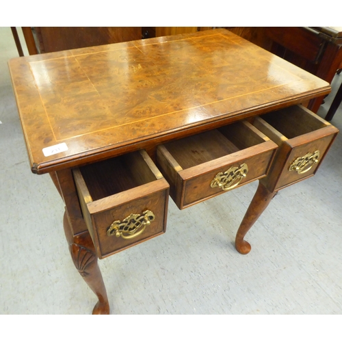 231 - A Georgian style walnut veneered lowboy with a burr veneered and string inlaid top, over three drawe... 