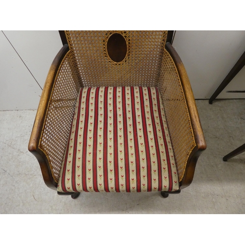 257 - An Edwardian mahogany framed bergere style, enclosed arm chair with woven cane panels, raised on cab... 