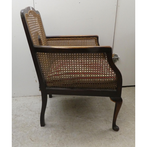 257 - An Edwardian mahogany framed bergere style, enclosed arm chair with woven cane panels, raised on cab... 