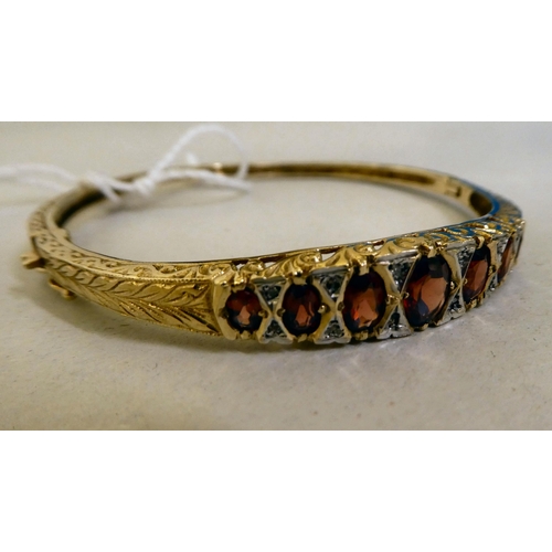 311 - A 9ct gold hinged bangle, set with diamonds and garnets 