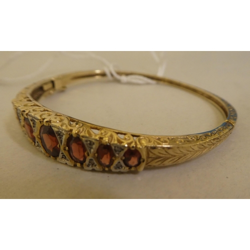 311 - A 9ct gold hinged bangle, set with diamonds and garnets 