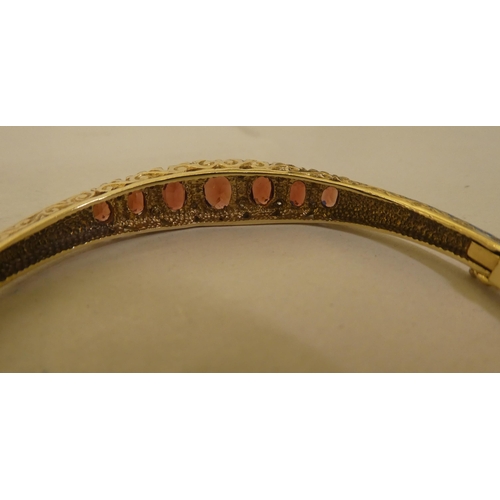 311 - A 9ct gold hinged bangle, set with diamonds and garnets 