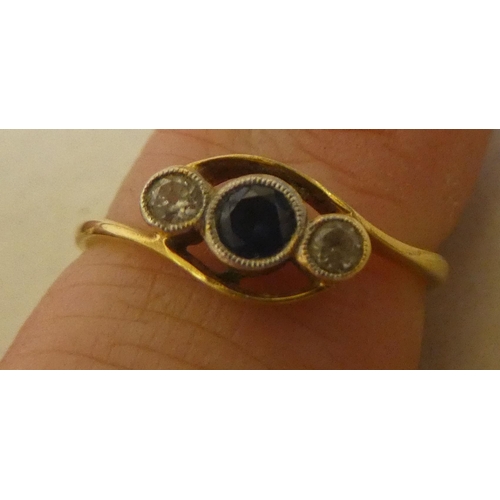 316 - A yellow metal ring, set with two diamonds and a sapphire, in a crossover setting  stamped 18k