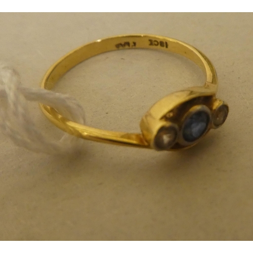 316 - A yellow metal ring, set with two diamonds and a sapphire, in a crossover setting  stamped 18k