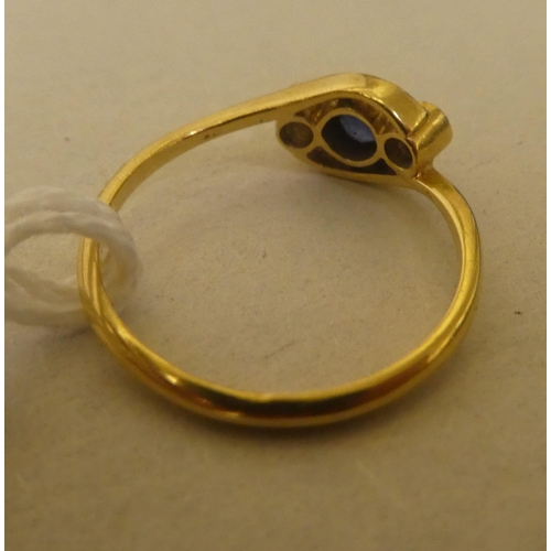 316 - A yellow metal ring, set with two diamonds and a sapphire, in a crossover setting  stamped 18k