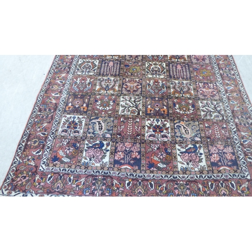 42 - A Persian rug, decorated with symmetrical, repeating floral designs, on a red ground  90