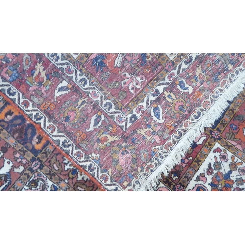 42 - A Persian rug, decorated with symmetrical, repeating floral designs, on a red ground  90