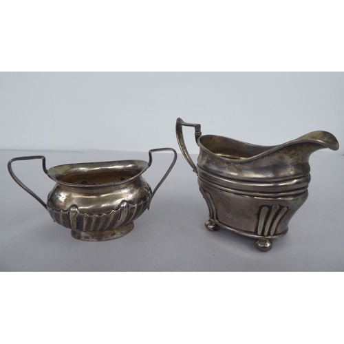 59 - An Edwardian silver oval cream jug, on bun feet  London 1905; and a contemporary silver twin ha... 